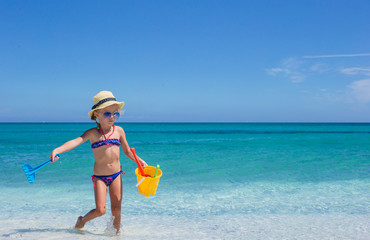 adorable little girl playing with toys on beach vacation