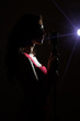 © M-Production - Silhouette of woman singing into vintage microphone.