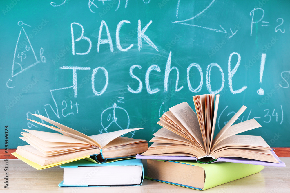 School supplies on table on blackboard background