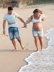 Wall Mural - Happy Pregnant couple on beach