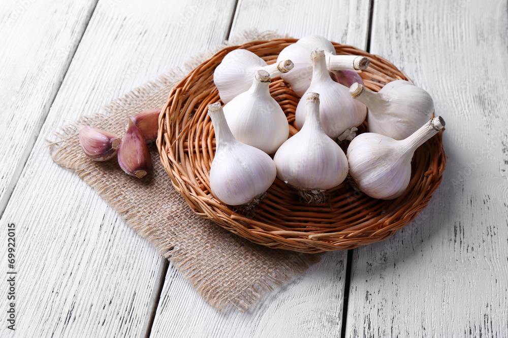 Fresh garlic on wicker mat, on wooden background