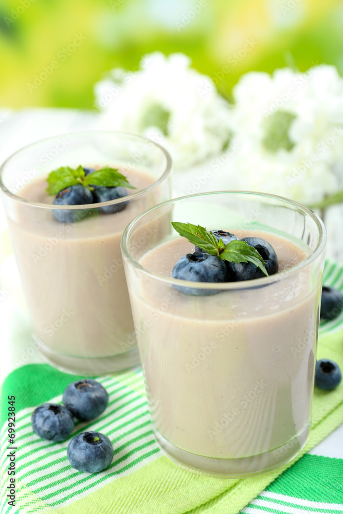 Delicious berry mousse in glasses on table on bright background