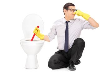 Wall Mural - Young man unclogging a stinky toilet with plunger