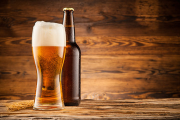 Glass and bottle of beer on wooden planks