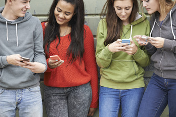 Group Of Teenagers Sharing Text Message On Mobile Phones