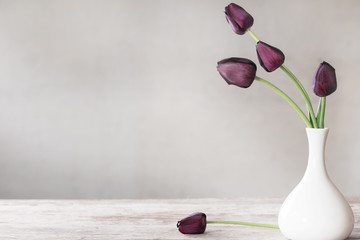 tulips in white vase on wooden table