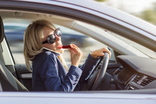 Busy Woman Talks On Phone And Does Makeup While Driving A Car