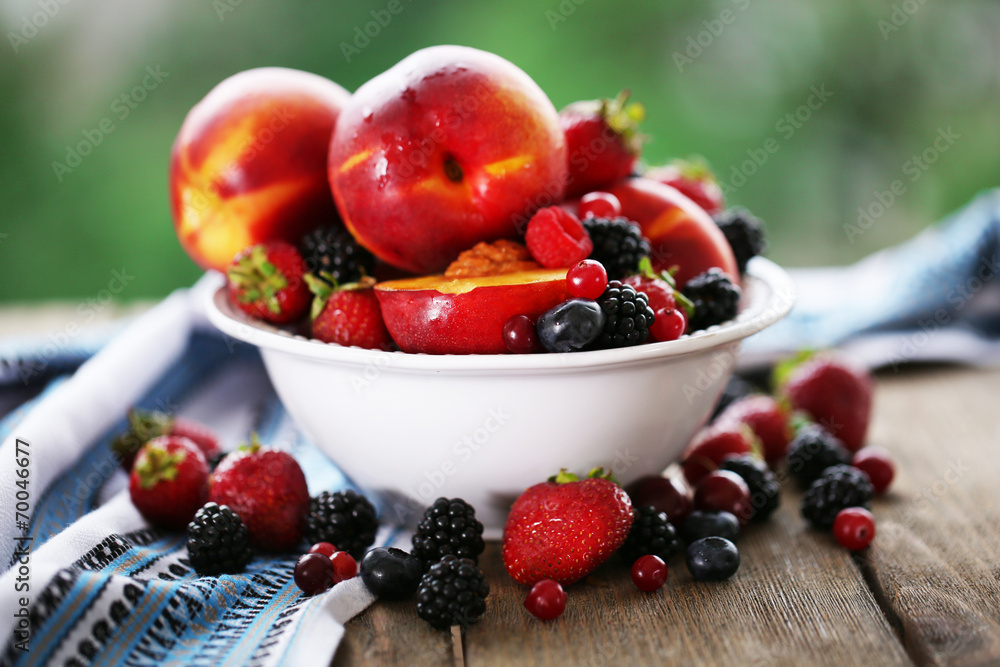 Peaches and berries in bowl on table close-up