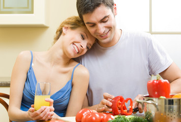 Wall Mural - Cheerful young cooking couple at home