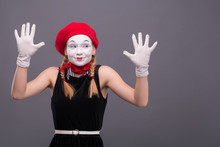 Portrait Of Female Mime With Red Hat And White Face Grimacing Wi