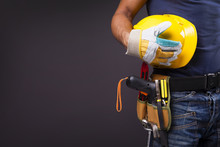 Close Up Of A Worker With Toolbelt And Helmet Against Black Back