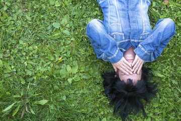 Young woman in a denim jacket lying on the grass