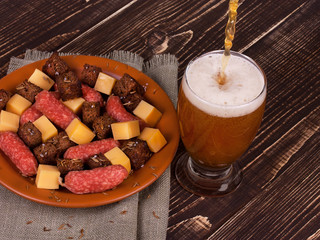 Wall Mural - Beer with cheese and sausage plate on wooden background