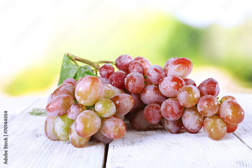 Bunch of ripe grape on wooden table on natural background