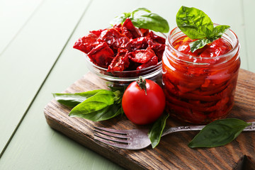 Wall Mural - Sun dried tomatoes in glass jar, basil leaves