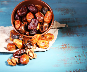 Wall Mural - Tasty dates fruits in bowl, on blue wooden background