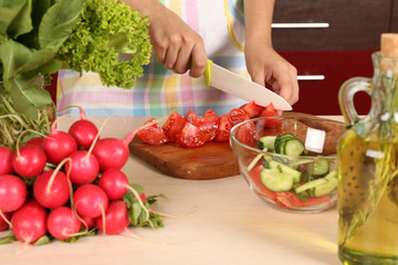 Wall Mural - Woman cooking vegetable salad in kitchen