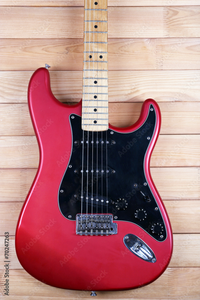 Red guitar on wooden background