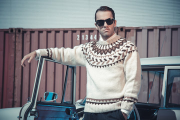 retro fifties fashion man with woolen sweater and sunglasses sta