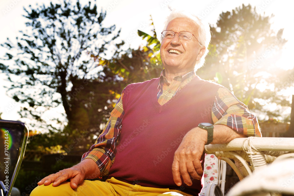 anziano seduto in giardino al tramonto - obrazy, fototapety, plakaty 