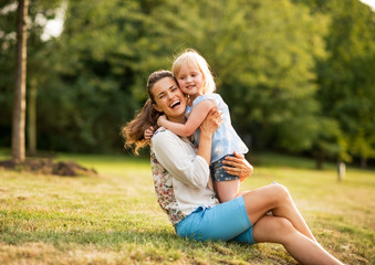 Wall Mural - Portrait of happy mother and baby girl hugging in park