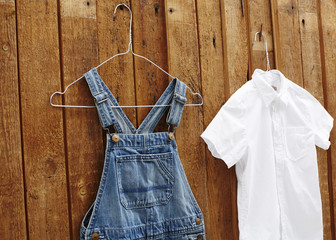 Wall Mural - Dungarees and white shirt hanging against wooden background.