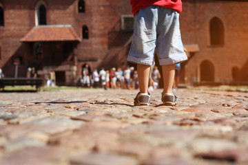 Legs of little kid boy  on the  stone road on the excursion