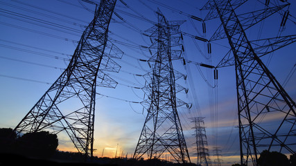 Silhouette of high power transmission towers at sunset