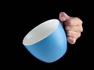 Woman hand holding an gentle blue color cup - mug on black backg