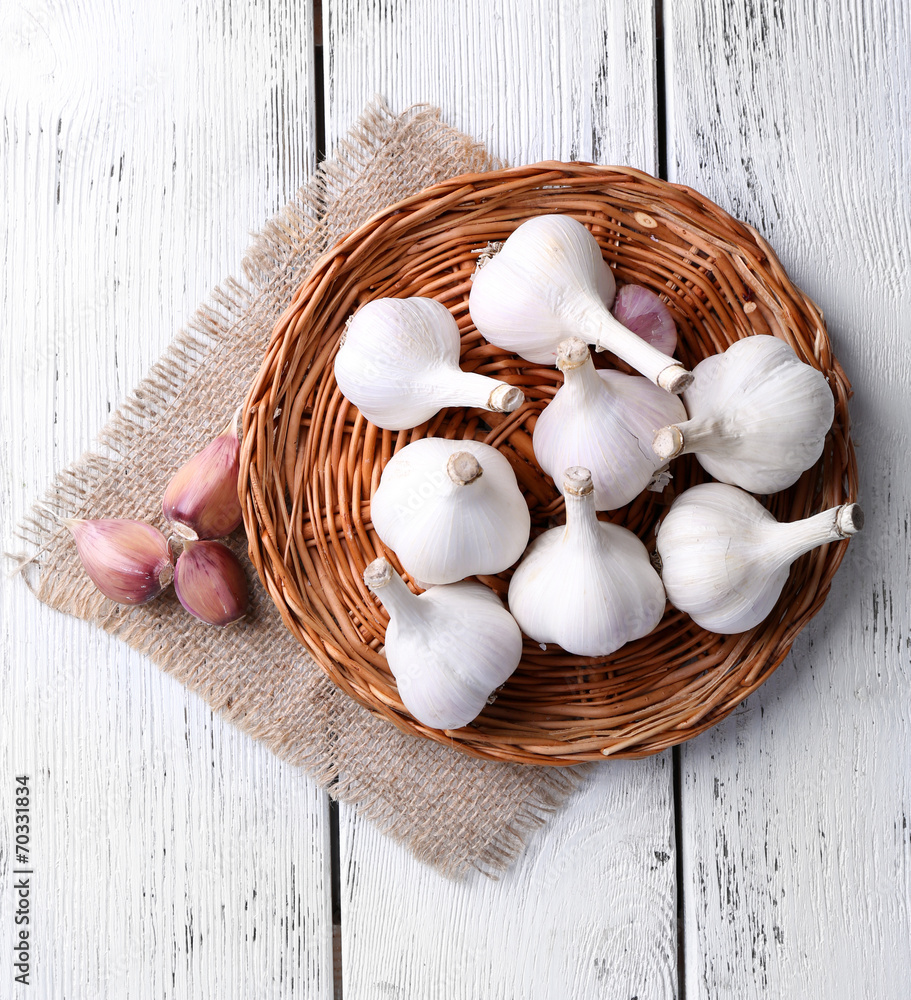 Fresh garlic on wicker mat, on wooden background