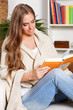© Imcsike - Beautiful young woman reading a book at home