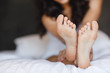 Beautiful feet of a young woman lying in bed close up. 