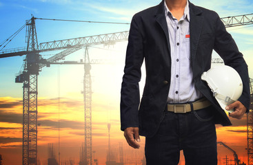 engineer man working with white safety helmet against crane and