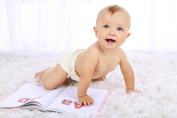 Wall Mural - Cute baby boy with book on carpet in room