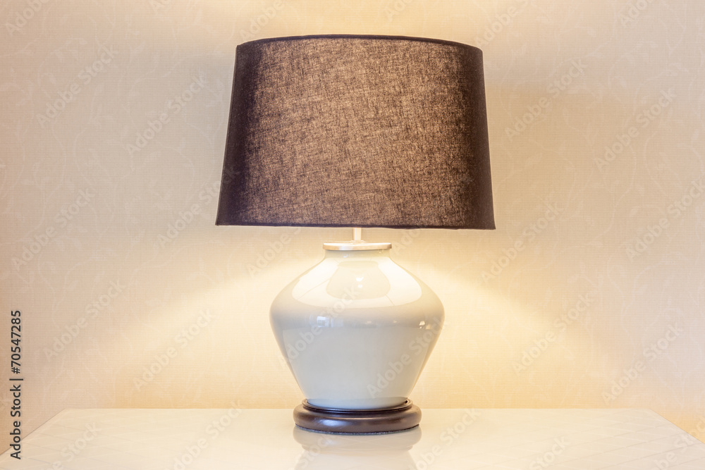 Table lamp and its shadow on wallpaper in the bedroom - obrazy, fototapety, plakaty 