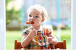 Cute baby girl eating sausage from fork