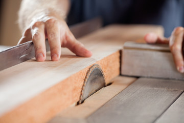 carpenter's hands cutting wood with tablesaw