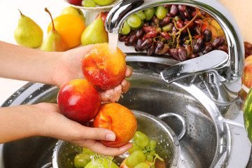 Wall Mural - Woman's hands washing peaches and other fruits in colander in