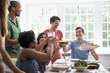 © Mint Images - A family gathering; men; women and children around a dining table sharing a meal.