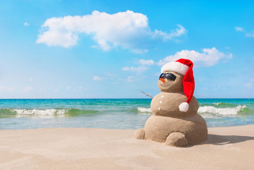 Poster - Christmas snowman in santa hat at sandy beach