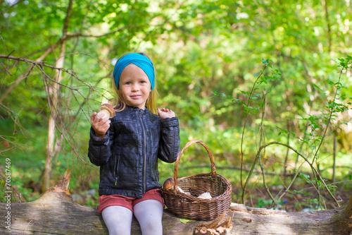 Stampe Little girl gathering mushrooms in an autumn forest