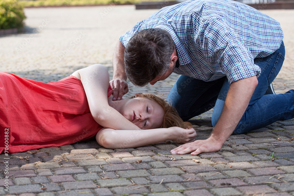 Man checking pulse of fainted girl - obrazy, fototapety, plakaty 