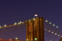 Close Up Of A Pillar Of The Brooklyn Bridge With Flag At Night