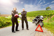 Zwei Motorradfahrer mit Panne stehen wartend auf der Strasse