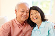 Senior Asian Couple Sitting On Sofa At Home Together