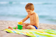 © Olesia Bilkei - cute kid playing with toys in sand on the beach