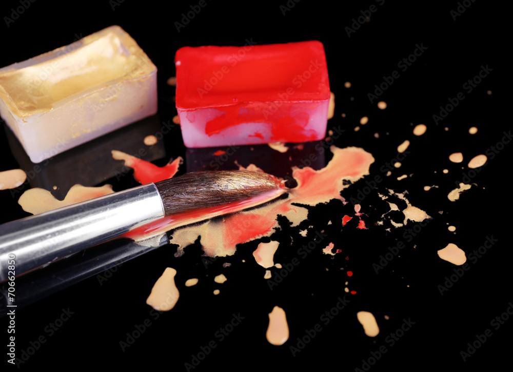 Watercolor paint cubes with brushes and spilled paint isolated