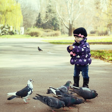 Cute Fashionable Baby Girl Feeding A Pigeons At The Autumn Park