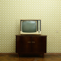 Retro tv with wooden case in room with vintage wallpaper and par