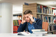 © vladgeorgescu - Bored male university student in the library studying for exam